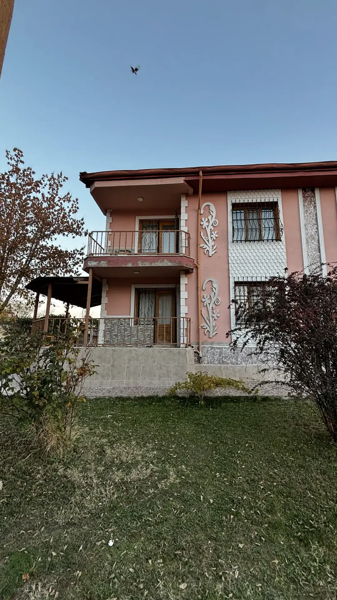 The balconied façade with white relief ornaments, facing the lawn